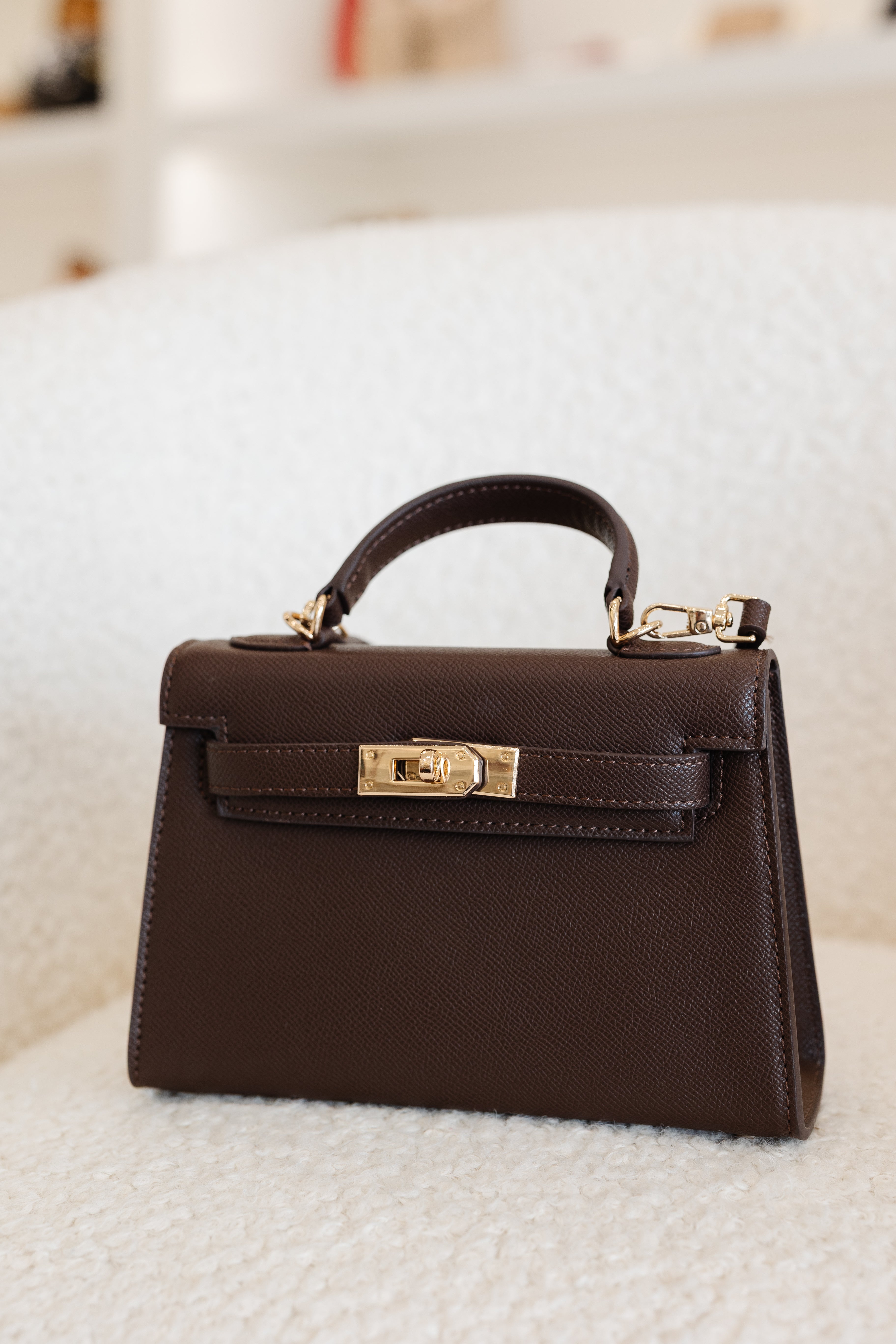 Brown handbag with gold hardware on a white surface