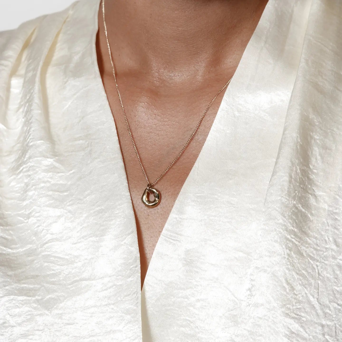 Gold necklace on a person wearing a white garment