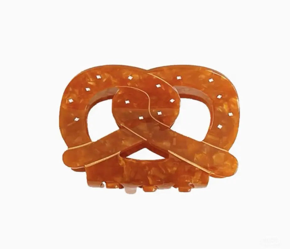 Orange plastic pretzel-shaped puzzle on a white background